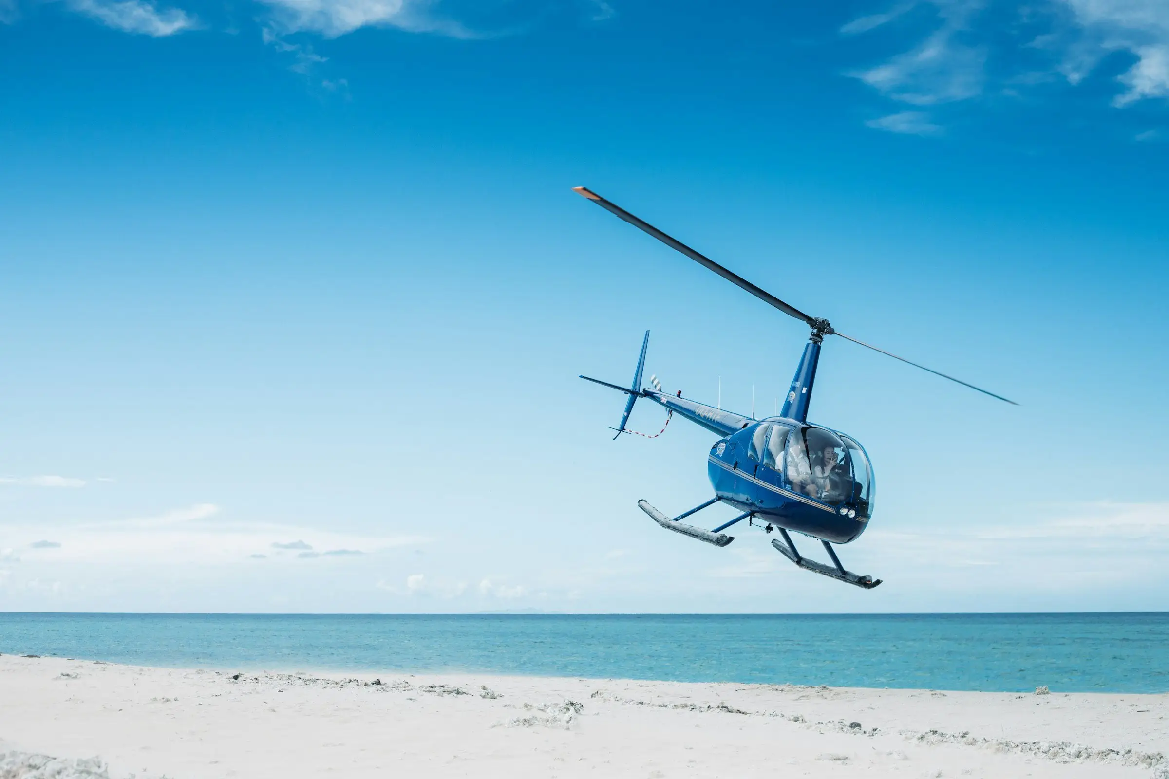 Hélicoptère en approche d’une plage de sable blanc
